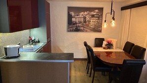 A compact kitchen with a toaster, sink, and a dining area with a table and chairs. - Apartment 'Andys Bergglück' with Mountain View, Balcony and Wi-Fi (Leutasch)