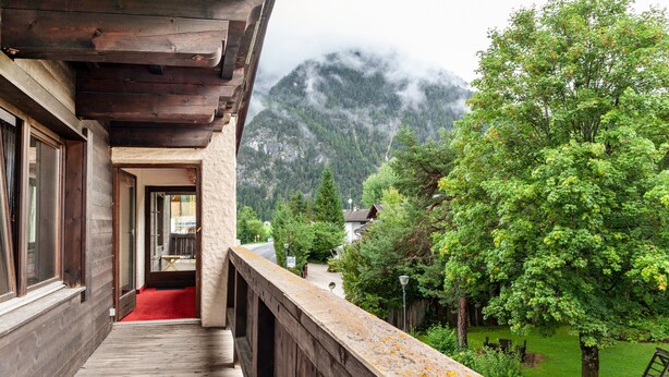 A wooden balcony with a red carpet, overlooking a lush green landscape and mountains. - Apartment 'Andys Bergglück' with Mountain View, Balcony and Wi-Fi (Leutasch)