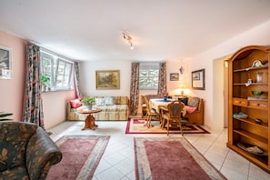 Un salon confortable avec un canapé, une table à manger et des chaises. On y trouve également une bibliothèque et une fenêtre avec des rideaux.