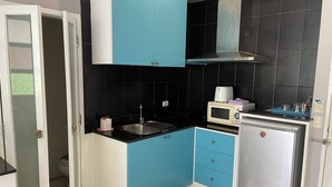 Una cucina compatta con lavello, forno a microonde e frigorifero.