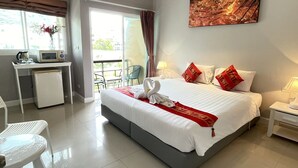 Una camera d'albergo con un letto, una scrivania, una sedia, un piccolo frigorifero e una finestra con tende.