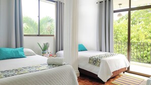 A hotel room with two beds, a large window, and a view of greenery outside. - Walena Hotel (Riohacha)