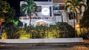 A modern hotel with a prominent logo, a balcony with colorful geometric patterns, and a well-lit entrance. - Walena Hotel (Riohacha)