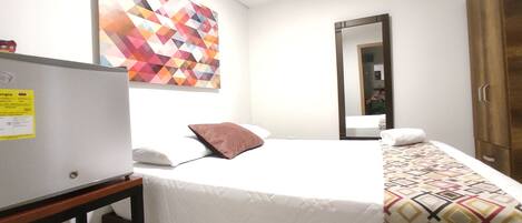 A hotel room with a bed, a mirror, a wardrobe, and a wall with a geometric pattern.