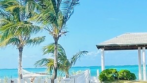 A pathway leading to a beach with palm trees and a gazebo. - Blue Ocean Village (Nassau)