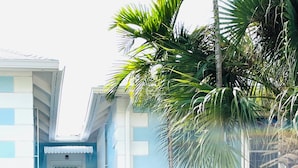 A two-story building with a light blue exterior, a white door, and a staircase leading to the entrance. - Blue Ocean Village (Nassau)