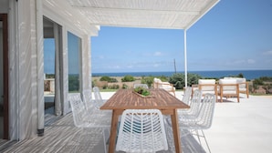 An outdoor patio with a wooden table and white chairs, overlooking a scenic view of the ocean. - TD Villa Maestrale Luxury Pool Sea View (Monopoli)