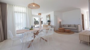 A spacious living area with a dining table, white wicker chairs, a grey sofa, and a round wooden coffee table. - TD Villa Maestrale Luxury Pool Sea View (Monopoli)