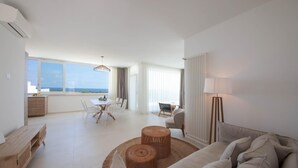 A spacious living area with a large window offering a view of the sea, a dining area with a table and chairs, and a cozy seating area with a sofa and a lamp. - TD Villa Maestrale Luxury Pool Sea View (Monopoli)