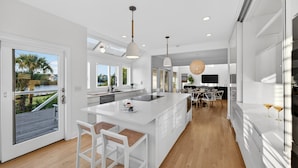 A modern kitchen with a large island, pendant lighting, and a view of the outdoors. - Luxurious Contemporary 4 BR Home, Golf Views! One Block to Beach! (Seabrook Island)