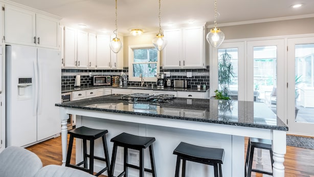 A modern kitchen with white cabinets, a large island with bar stools, stainless steel appliances, and pendant lighting. - 3 BR 2 bath 5 beds! sleeps 8. Pool, hot tub oasis in LEX (Lexington)