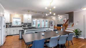 A modern kitchen with a large island, white cabinets, and a dining area with a wooden table and chairs. - 3 BR 2 bath 5 beds! sleeps 8. Pool, hot tub oasis in LEX (Lexington)