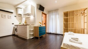 A modern bedroom with a wooden bed, a built-in wardrobe, a washing machine, and a TV mounted on the wall. - Via Duomo 196 in Naples (Naples)
