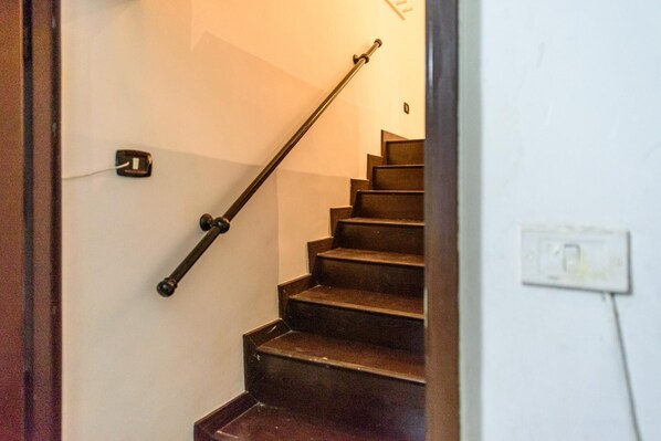 A staircase with wooden steps and a metal handrail, leading to an upper floor.