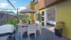 A patio with a table and chairs, a car, and a sliding glass door leading to a bedroom. - Tahuna Beach Oasis - Home in the heart of Tahunanui Beach recreational paradise (Nelson)