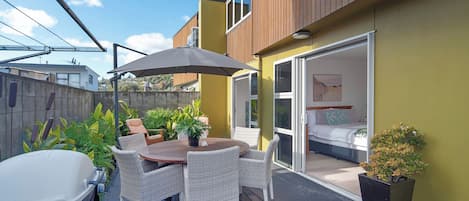 A patio with a table and chairs, a car, and a sliding glass door leading to a bedroom.