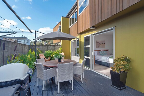 A patio with a table and chairs, a car, and a sliding glass door leading to a bedroom.