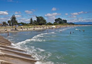 A beach with waves, people, and umbrellas.