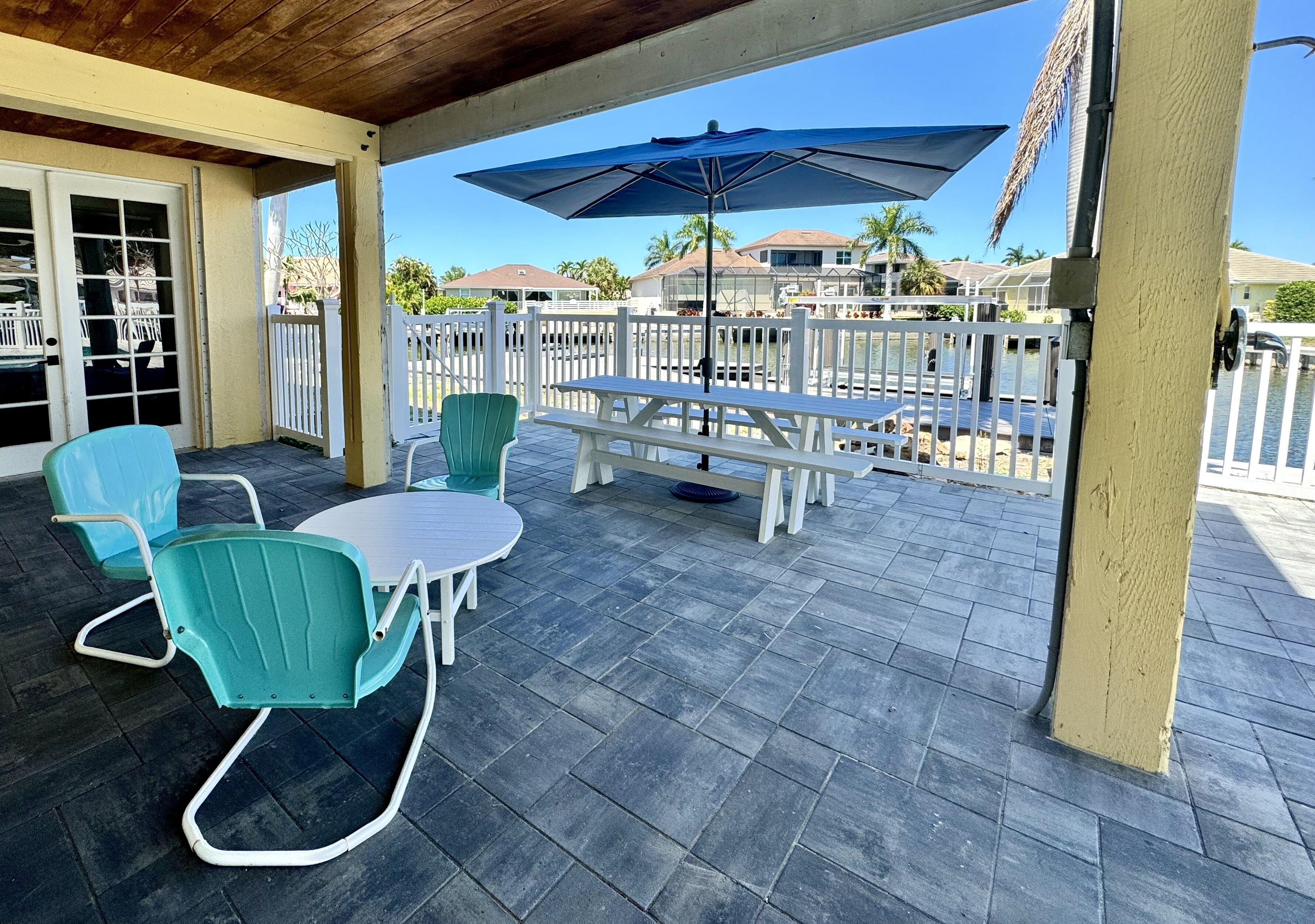 A covered patio area with a table and chairs, a bench, and a large umbrella.