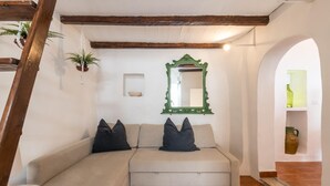 A cozy room with a beige sectional sofa, a green-framed mirror, and a small shelf with a green bottle and a ceramic jug. - Biancostuni 44, The Little White Houses (Ostuni)