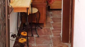 Un pasillo estrecho con un armario de madera, una silla y una cama con una colcha estampada.