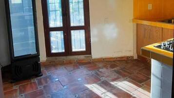 A kitchen with a tiled floor, wooden cabinets, and a refrigerator.