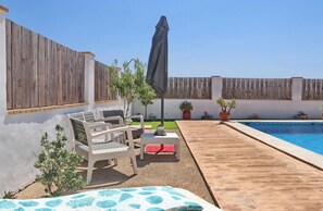 A backyard with a pool, outdoor furniture, and potted plants.