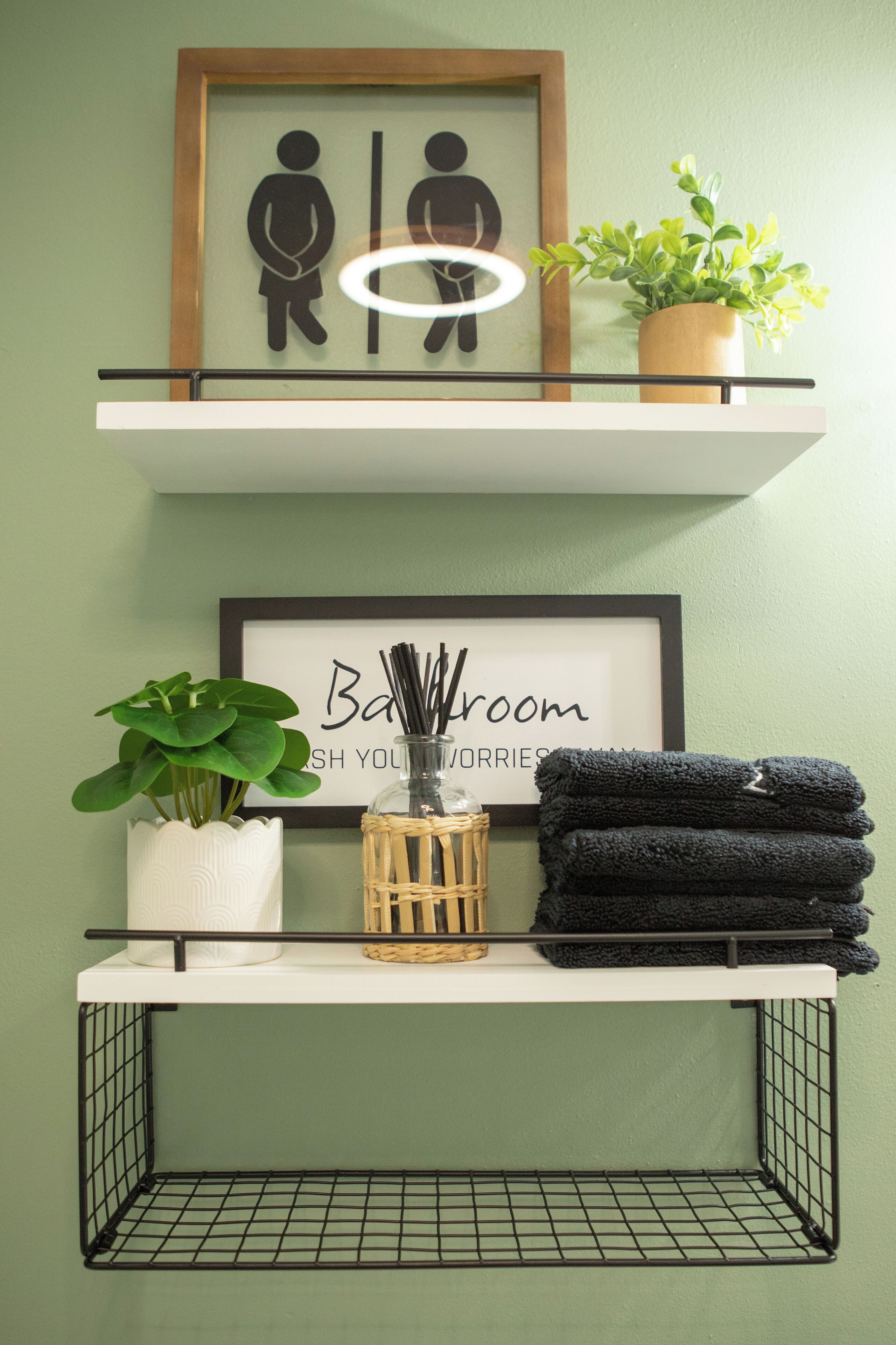 A bathroom vanity with a framed picture, a potted plant, a basket, and folded towels.