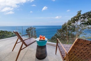 A balcony with wicker chairs and a table with drinks, overlooking a clear blue sea. - Villa La Prana (Kamala)