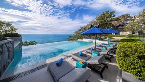 An infinity pool with lounge chairs and umbrellas, overlooking a body of water. - Villa La Prana (Kamala)