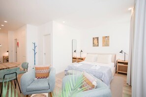 Una habitación de hotel moderna con una cama, dos sillas, una mesita y una mesita de noche.