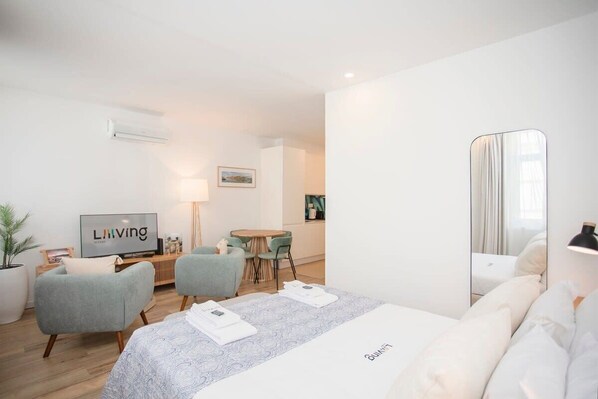 Una habitación de hotel moderna con cama, televisor, escritorio y zona de comedor.