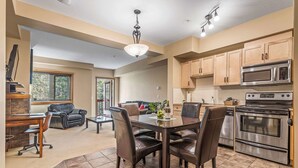 A spacious kitchen with modern appliances, a dining area with leather chairs, and a view of the outdoors. - Spacious King Bed with Pool & Hot Tubs (Canmore)