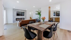 A modern dining area with a wooden table, black chairs, and a central vase with flowers. - 246A- Modern 3B2B w/ Deck & View by Hillsdale Mall (San Mateo)