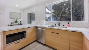 A modern kitchen with a dishwasher, microwave, and wooden cabinets. - 246A- Modern 3B2B w/ Deck & View by Hillsdale Mall (San Mateo)