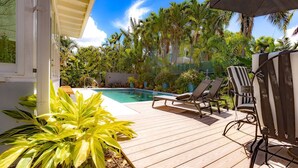 A wooden deck with a pool, lounge chairs, and a covered area with an umbrella. - Vahevala: Your Tranquil Mid-Town Key West Oasis, 3BR Home, Pool & Close to Beaches & Duval Street! (Key West)