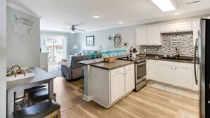 A modern kitchen with white cabinets, a central island, and a dining area with a table and chairs.