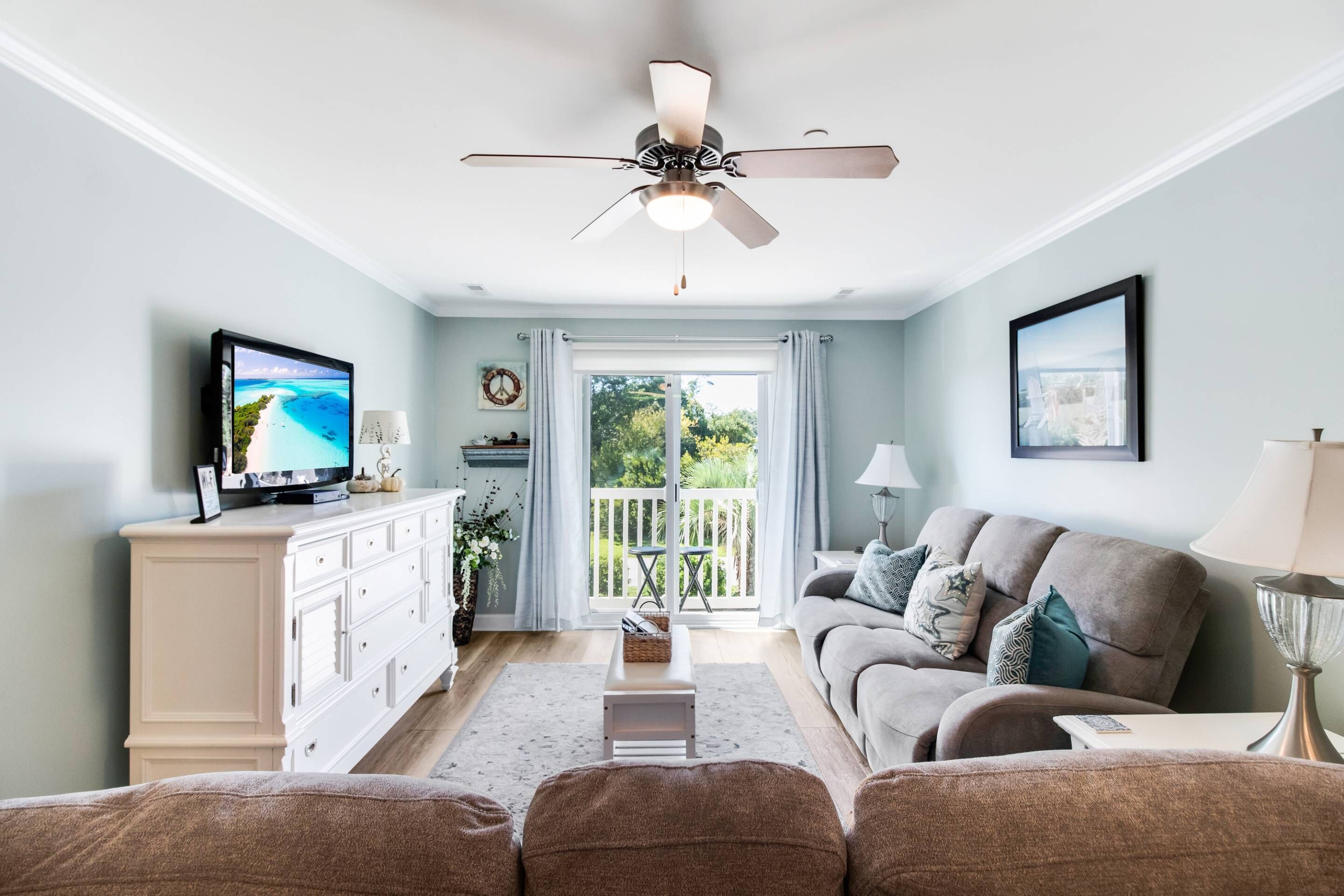 A living room with a television, sofa, and a ceiling fan.