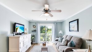 A living room with a television, sofa, and a ceiling fan.