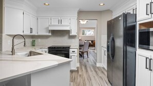 A modern kitchen with white cabinetry, a stainless steel refrigerator, and a built-in oven. - Exceptional Pet Friendly Home, Game Room w/ Pool Table, Large Deck and Seating, 5 Miles to Portland (Portland)