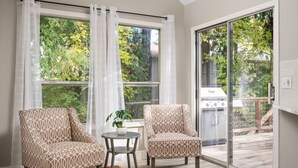 A sunlit room with two patterned chairs, a small table with a plant, and a sliding glass door leading to an outdoor deck. - Exceptional Pet Friendly Home, Game Room w/ Pool Table, Large Deck and Seating, 5 Miles to Portland (Portland)