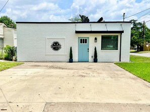 Un petit bâtiment d’un seul étage, avec une porte bleu clair et une porte de garage.