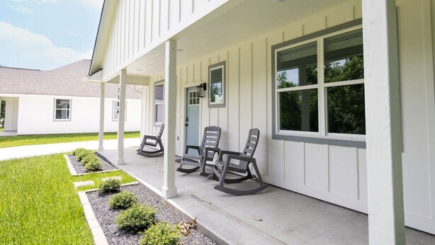 A covered porch with three rocking chairs, a door, and windows. - Modern Nest - Brand New House w/ modern amenities (Bryan)
