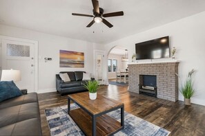 A modern living room with a sofa, coffee table, fireplace, and a ceiling fan.