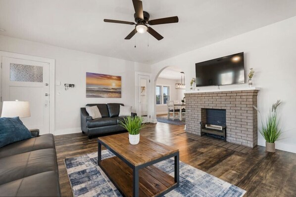 Un salon moderne avec un canapé, une table basse, une cheminée et un ventilateur de plafond.