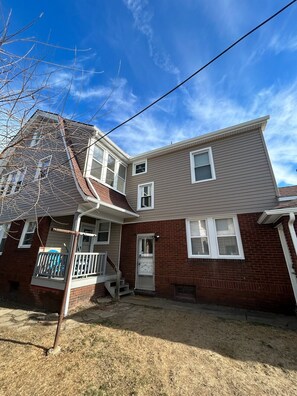 A two-story house with a front porch, a garage, and a brick exterior.
