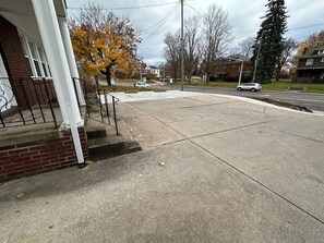 A residential street with a sidewalk, a brick house with a porch, and autumn trees. - Larger 2 Bedroom Apt in the Heart of Canton, Minutes From HOF and Both Hospitals (Canton)