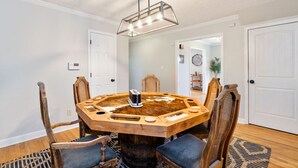 Un comedor con una mesa redonda de madera, seis sillas y una lámpara colgante moderna.