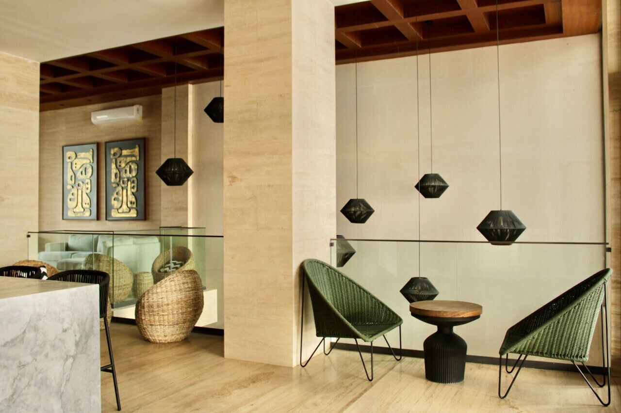 Un intérieur moderne avec une cloison en verre, des fauteuils en osier et des motifs géométriques décorant les murs.