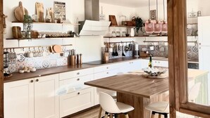 Una cocina moderna con armarios blancos, encimeras de madera y una isla central con taburetes.